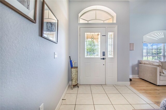 413 Ruby Lake Pl, Winter Haven, FL 33884 - foyer with a textured wall, baseboards, light tile patterned floors, and arched walkways