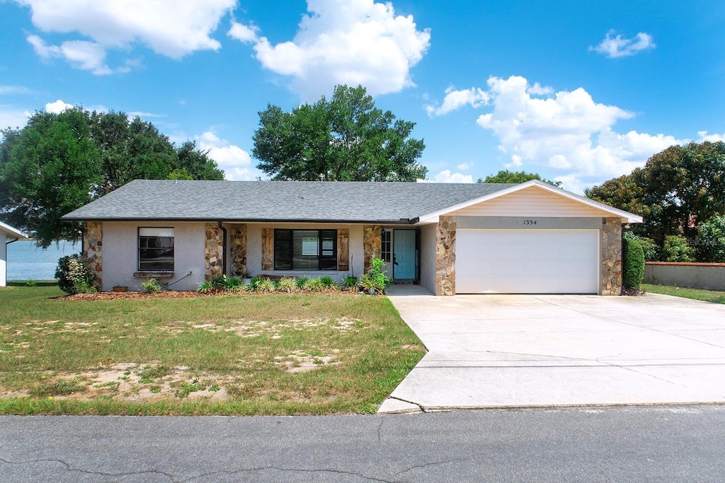 1334 Highland Park Dr S, Lake Wales, FL 33898 - single story home featuring stone siding, an attached garage, and a front lawn