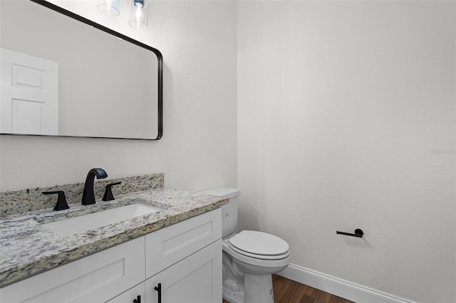 2052 W Elliott St, Lakeland, FL 33805 - bathroom with wood finished floors, vanity, toilet, and baseboards