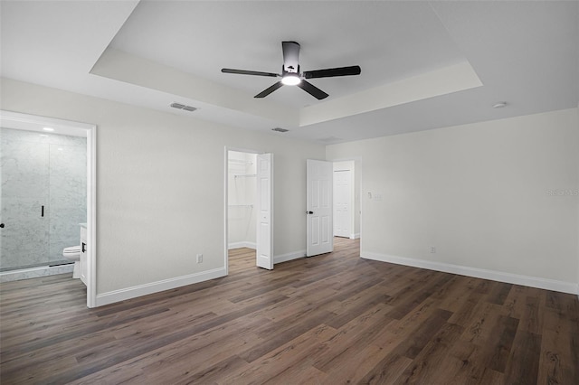 2052 W Elliott St, Lakeland, FL 33805 - unfurnished bedroom featuring a tray ceiling, wood finished floors, baseboards, a walk in closet, and ensuite bath