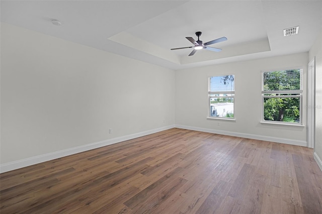 2052 W Elliott St, Lakeland, FL 33805 - empty room with a tray ceiling, wood finished floors, baseboards, and a ceiling fan