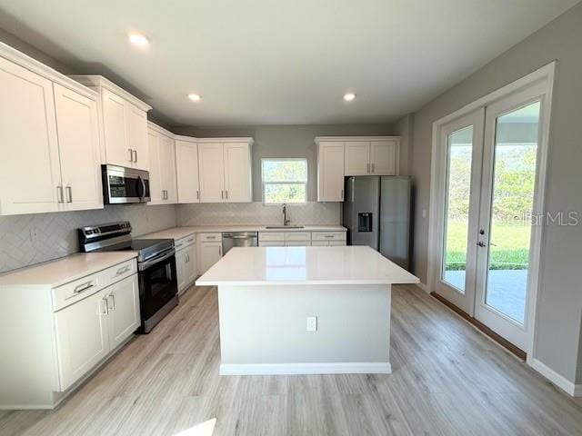 4956 San Lorenzo Dr, Sebring, FL 33872 - kitchen with stainless steel appliances, a sink, a kitchen island, tasteful backsplash, and white cabinetry