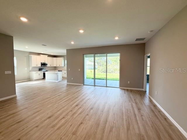 4956 San Lorenzo Dr, Sebring, FL 33872 - unfurnished living room with light wood-style floors, recessed lighting, and baseboards