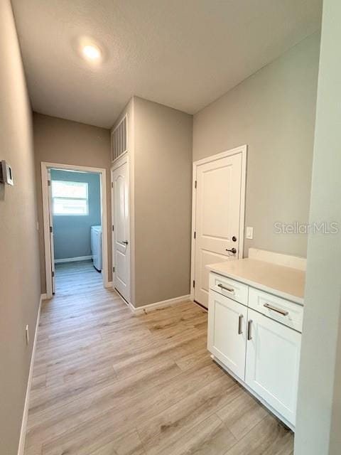 4956 San Lorenzo Dr, Sebring, FL 33872 - corridor with light wood-style floors, baseboards, and washer and clothes dryer