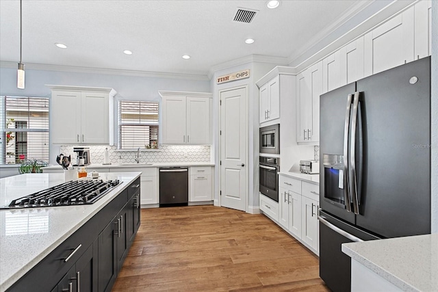 505 Adams View Ln, Auburndale, FL 33823 - kitchen with stainless steel appliances, white cabinets, ornamental molding, decorative light fixtures, and decorative backsplash