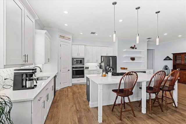 505 Adams View Ln, Auburndale, FL 33823 - kitchen with stainless steel appliances, a sink, crown molding, wood finished floors, and white cabinetry