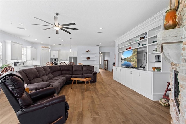 505 Adams View Ln, Auburndale, FL 33823 - living room featuring ceiling fan, a stone fireplace, light wood finished floors, crown molding, and recessed lighting