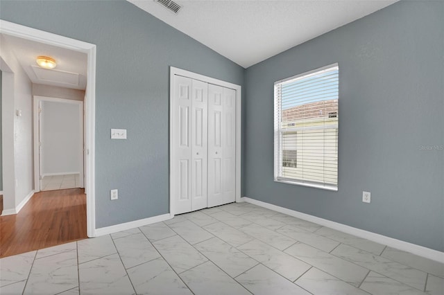 362 Lake Daisy Cir, Winter Haven, FL 33884 - unfurnished bedroom with light marble finish flooring, a closet, lofted ceiling, attic access, and baseboards