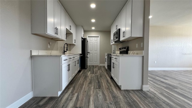 1735 Council Dr, Sun City Center, FL 33573 - kitchen featuring stainless steel appliances, a sink, dark wood-style flooring, baseboards, and light countertops