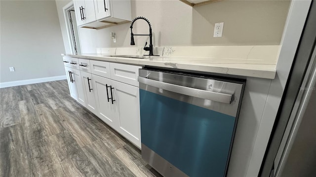 1735 Council Dr, Sun City Center, FL 33573 - kitchen with dishwasher, a sink, light stone countertops, white cabinets, and wood finished floors