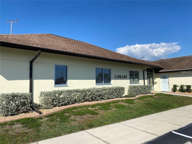 1735 Council Dr, Sun City Center, FL 33573 - view of home's exterior with stucco siding, a shingled roof, and a lawn