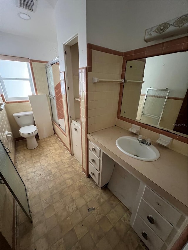 507 Ave H SE, Winter Haven, FL 33880 - bathroom featuring toilet, vanity, tile walls, shower / bath combination with glass door, and stone finish floors