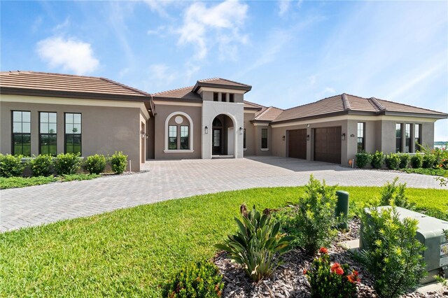 209 Pine Lilly Ct, Lake Alfred, FL 33850 - mediterranean / spanish-style home with an attached garage, stucco siding, decorative driveway, a tile roof, and a front lawn