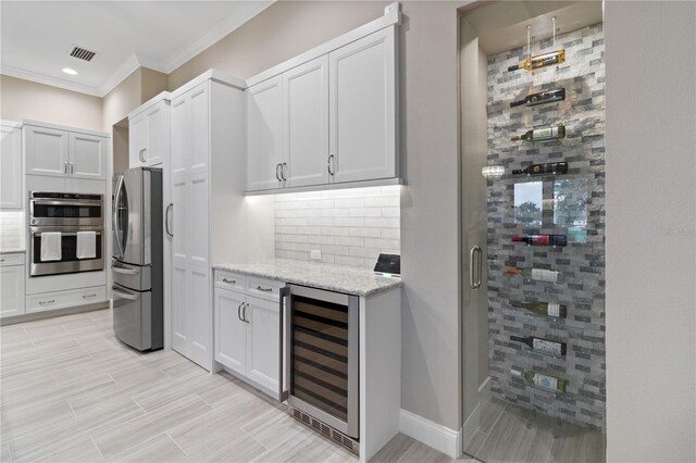 209 Pine Lilly Ct, Lake Alfred, FL 33850 - kitchen featuring appliances with stainless steel finishes, wine cooler, tasteful backsplash, crown molding, and light stone countertops
