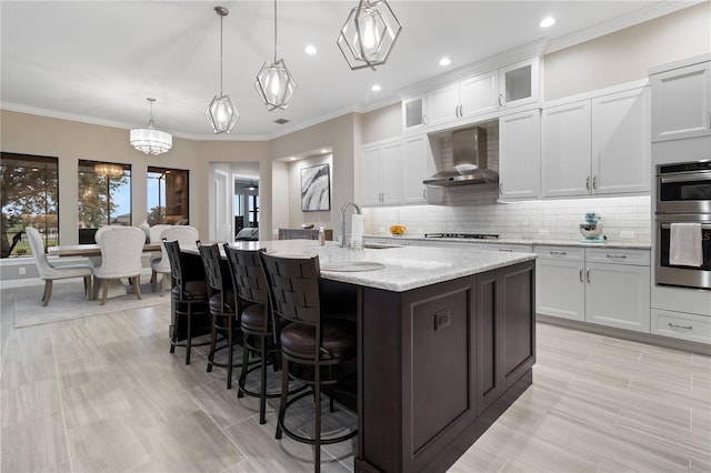 209 Pine Lilly Ct, Lake Alfred, FL 33850 - kitchen with wall chimney range hood, stovetop, a breakfast bar area, double oven, and an island with sink