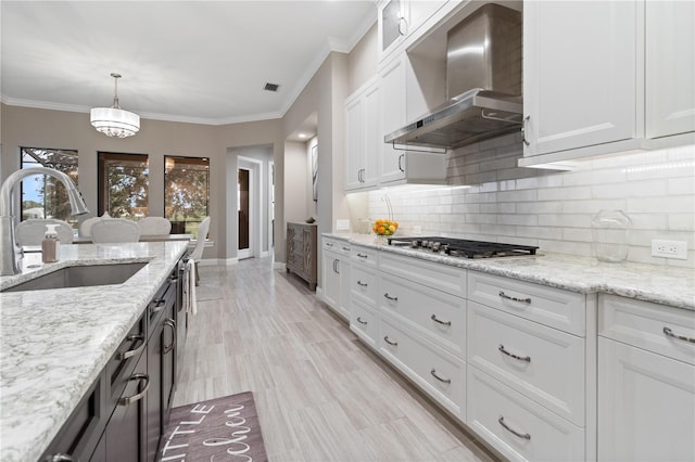 209 Pine Lilly Ct, Lake Alfred, FL 33850 - kitchen with wall chimney range hood, a sink, stainless steel gas cooktop, white cabinets, and tasteful backsplash