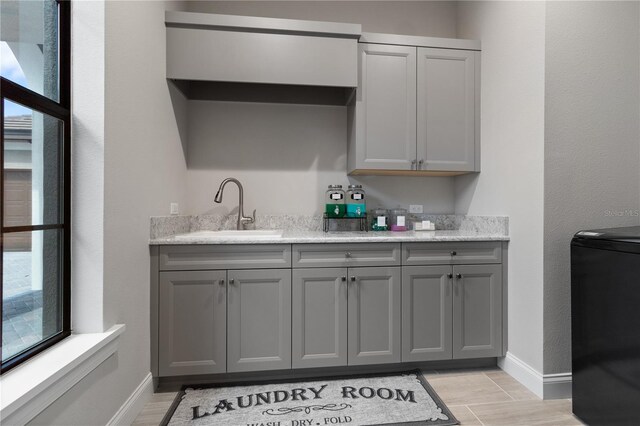 209 Pine Lilly Ct, Lake Alfred, FL 33850 - kitchen with gray cabinetry, a sink, baseboards, and light wood-style flooring