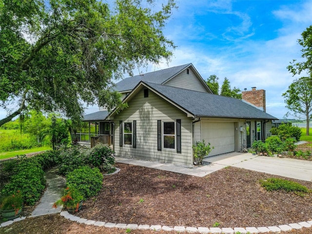 1256 Center St, Dundee, FL 33838 - view of front of house with concrete driveway, a garage, a chimney, and a shingled roof