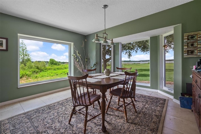 1256 Center St, Dundee, FL 33838 - dining area with light tile patterned flooring, a textured ceiling, a chandelier, and baseboards