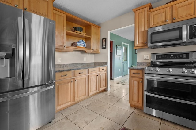 1256 Center St, Dundee, FL 33838 - kitchen with appliances with stainless steel finishes, open shelves, light tile patterned flooring, and dark stone counters
