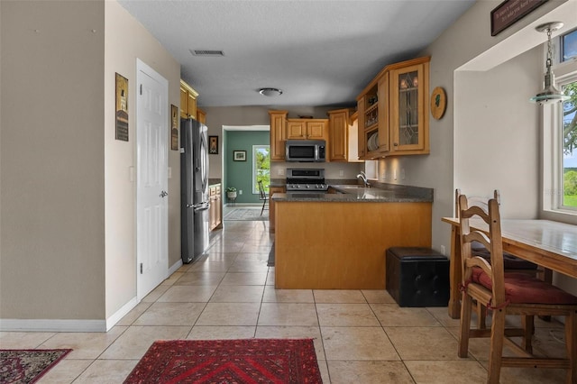 1256 Center St, Dundee, FL 33838 - kitchen featuring stainless steel appliances, a sink, glass insert cabinets, dark countertops, and a peninsula
