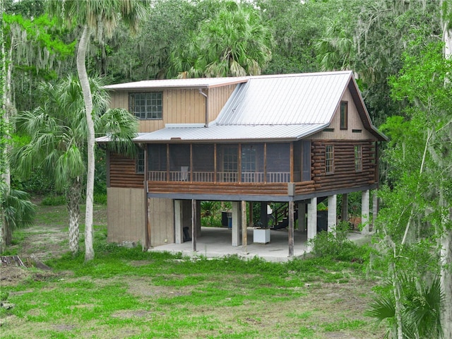 2530 Arbuckle Shores Rd, Frostproof, FL 33843 - rear view of property featuring a sunroom, a patio area, a carport, metal roof, and log siding