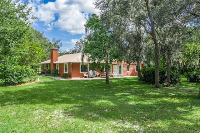 1273 Scrub Jay Trl, Frostproof, FL 33843 - rear view of property with a chimney, a yard, and a metal roof