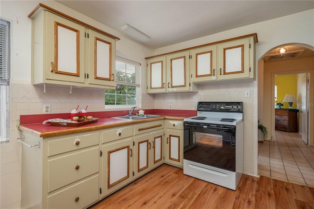 304 W Lake Ave, Auburndale, FL 33823 - kitchen featuring range with electric stovetop, a sink, arched walkways, and light wood-style flooring