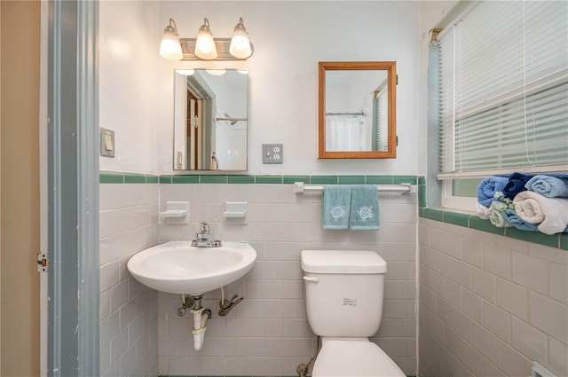 304 W Lake Ave, Auburndale, FL 33823 - bathroom with toilet, tile walls, wainscoting, and a sink