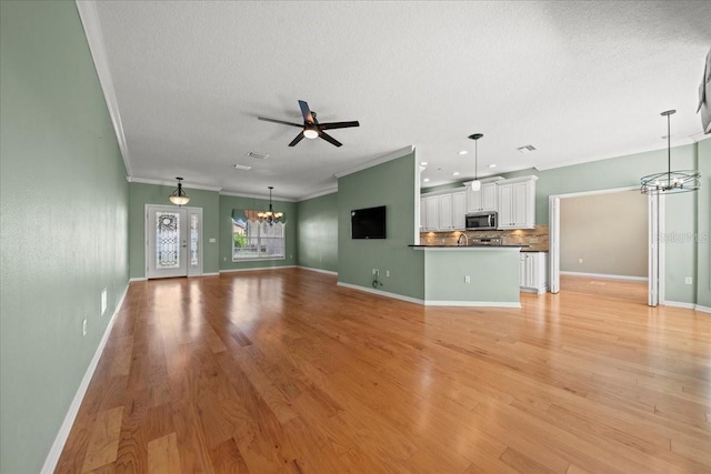 4254 Berwick Dr, Lake Wales, FL 33859 - unfurnished living room featuring a chandelier, ornamental molding, a textured ceiling, light wood-style floors, and ceiling fan