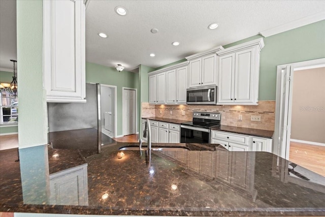 4254 Berwick Dr, Lake Wales, FL 33859 - kitchen with stainless steel appliances, backsplash, dark stone counters, recessed lighting, and white cabinetry