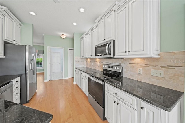 4254 Berwick Dr, Lake Wales, FL 33859 - kitchen with appliances with stainless steel finishes, light wood-style floors, backsplash, white cabinetry, and dark stone countertops
