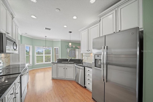 4254 Berwick Dr, Lake Wales, FL 33859 - kitchen featuring appliances with stainless steel finishes, a peninsula, ornamental molding, light wood-style floors, and backsplash