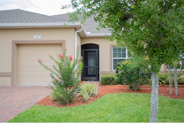 3023 Caneel, Winter Haven, FL 33884 - entrance to property featuring roof with shingles, stucco siding, an attached garage, and a lawn
