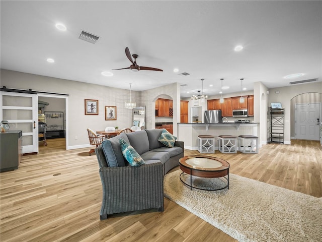 3802 Litchfield Loop, Lake Wales, FL 33859 - living room with arched walkways, ceiling fan, light wood-type flooring, a barn door, and a chandelier