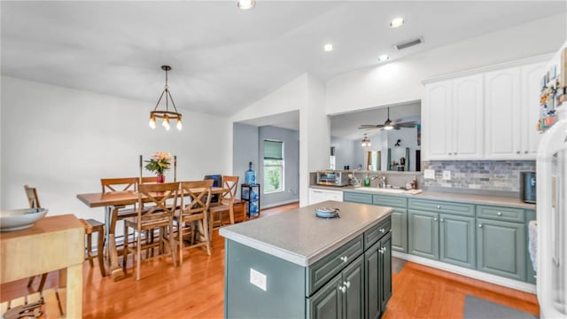 2602 Whitewood Rd, Mulberry, FL 33860 - kitchen with white cabinets, a kitchen island, lofted ceiling, decorative backsplash, and light wood-style flooring