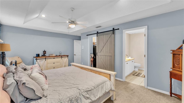 2602 Whitewood Rd, Mulberry, FL 33860 - bedroom with a barn door, light carpet, recessed lighting, connected bathroom, and a tray ceiling