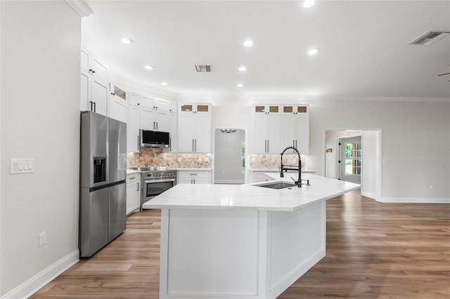 5820 E Johnson Ave, Haines City, FL 33844 - kitchen featuring stainless steel appliances, crown molding, decorative backsplash, a spacious island, and light wood-type flooring