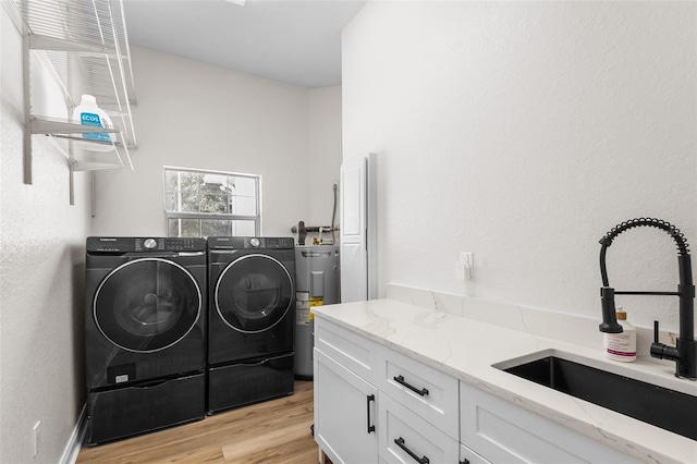 5820 E Johnson Ave, Haines City, FL 33844 - laundry room featuring washer and dryer, electric water heater, light wood finished floors, and cabinet space