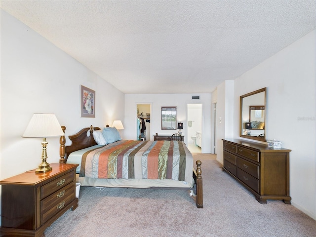 700 Mirror Ter NW Unit 702, Winter Haven, FL 33881 - bedroom with a walk in closet, light colored carpet, a closet, a textured ceiling, and ensuite bath