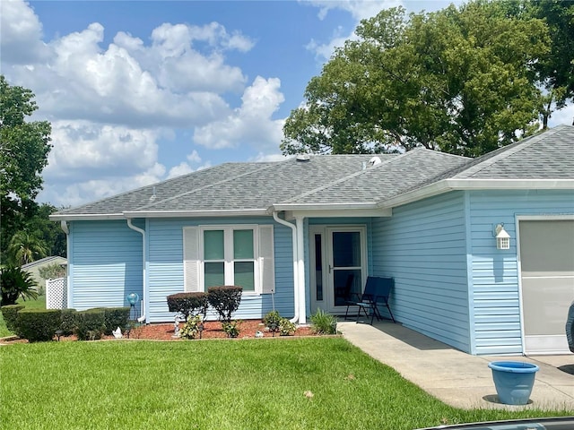 6192 Magpie Dr, Lakeland, FL 33809 - back of house with a lawn, a shingled roof, and an attached garage