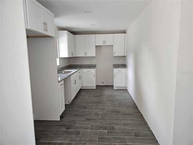 602 Lime Ave, Dundee, FL 33838 - kitchen with wood finish floors, white cabinetry, and stone countertops