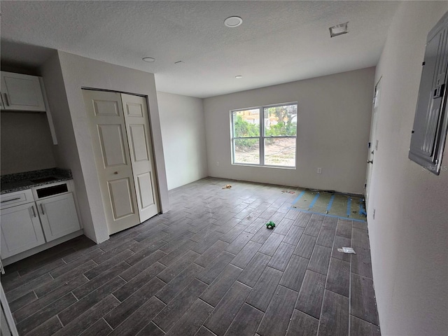 602 Lime Ave, Dundee, FL 33838 - kitchen featuring wood tiled floors, open floor plan, white cabinetry, dark stone countertops, and a textured ceiling