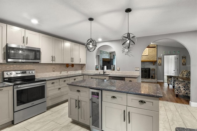704 Butternut Pl, Lakeland, FL 33813 - kitchen with stainless steel appliances, wine cooler, arched walkways, backsplash, and a kitchen island