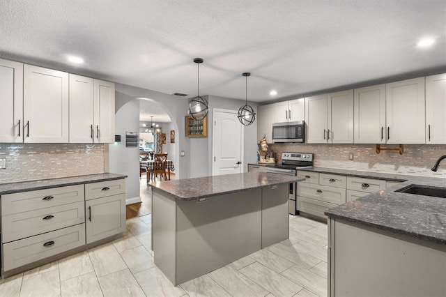 704 Butternut Pl, Lakeland, FL 33813 - kitchen with appliances with stainless steel finishes, arched walkways, backsplash, dark stone counters, and recessed lighting