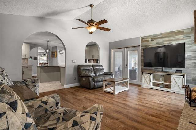 704 Butternut Pl, Lakeland, FL 33813 - living room featuring ceiling fan, wood finished floors, arched walkways, vaulted ceiling, and a textured ceiling