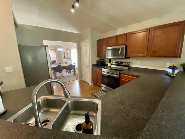 1790 Turtle Rock Dr, Lakeland, FL 33803 - kitchen with appliances with stainless steel finishes, brown cabinetry, vaulted ceiling, and a chandelier