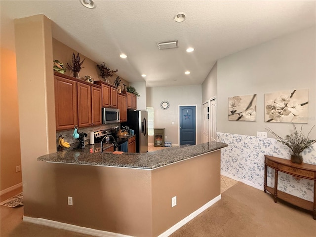 13443 Graham Yarden Dr, Riverview, FL 33579 - kitchen with stainless steel appliances, dark stone counters, light carpet, recessed lighting, and brown cabinetry