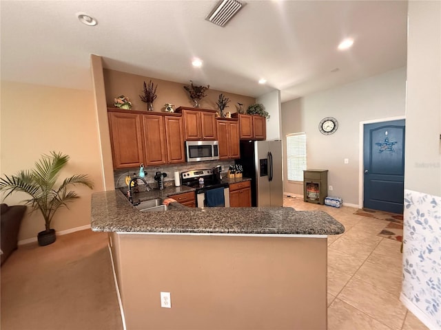 13443 Graham Yarden Dr, Riverview, FL 33579 - kitchen featuring appliances with stainless steel finishes, brown cabinets, a peninsula, decorative backsplash, and dark stone counters