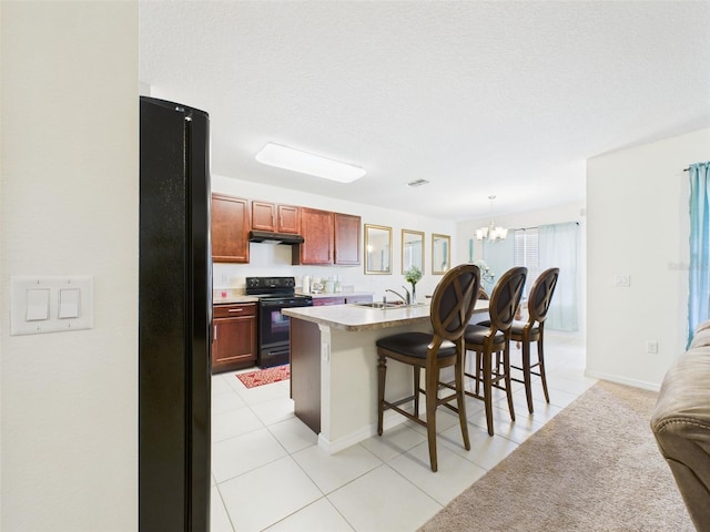 5751 Lakeside Landings Blvd, Winter Haven, FL 33881 - kitchen featuring black appliances, a chandelier, under cabinet range hood, a breakfast bar area, and a kitchen island with sink